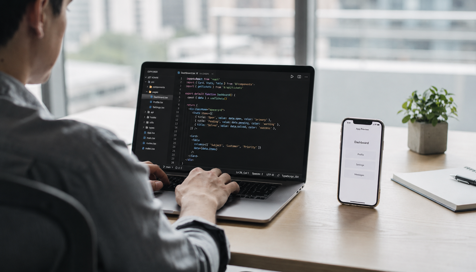 A person is focused on their laptop in a sleek, modern workspace, with lines of code visible on the screen, indicating they are engaged in ai powered code generation. Beside them, a mobile phone displays an app preview, showcasing the potential of ai powered app development.