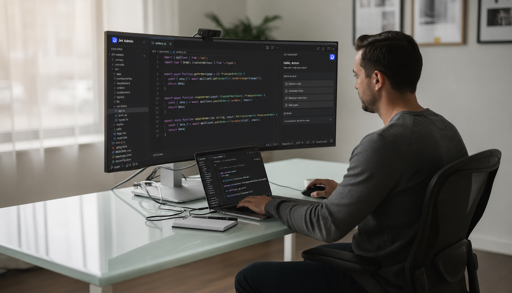 The image depicts a developer sitting at a desk, focused on a laptop and an external monitor displaying a code editor, specifically Visual Studio Code, which features colorful syntax highlighting. The coding environment suggests an advanced setup for software development, likely utilizing AI-assisted coding tools to enhance code quality and streamline the coding process.