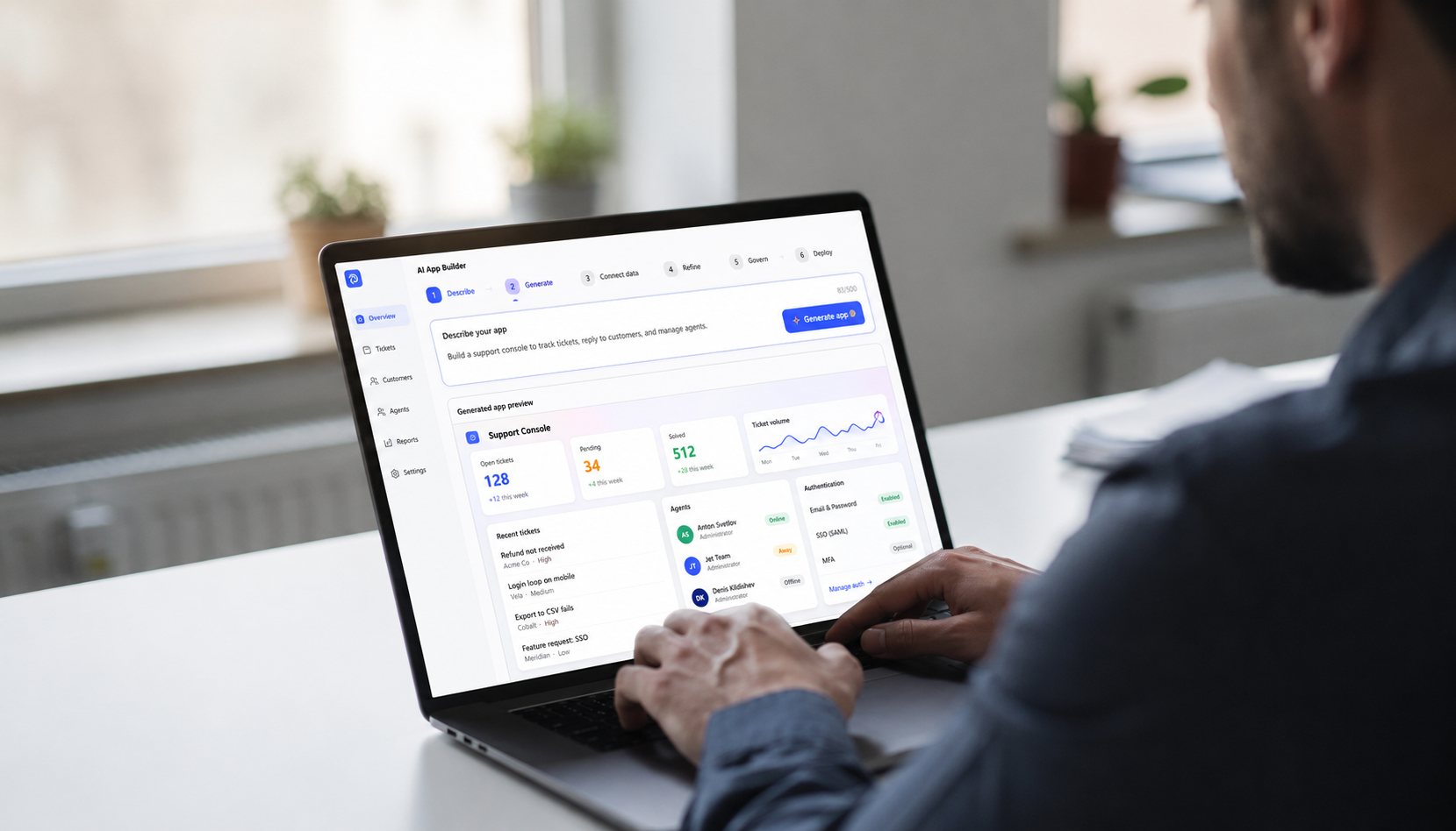 A person is seated at a desk, focused on their laptop which displays a vibrant web application interface showcasing user management features and user authentication options. The colorful design suggests an AI app builder aimed at non-technical users, facilitating app development and integration with tools like Google Sheets and Google Drive.