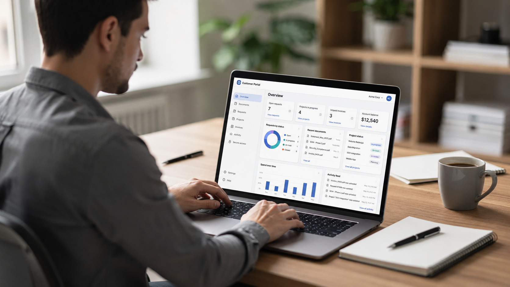 A person is sitting at a desk, focused on their laptop displaying a clean client portal dashboard interface featuring various charts and document icons. This user-friendly interface facilitates project management and secure file sharing, enhancing customer satisfaction and engagement.